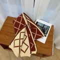 Gestrickter Schal mit Karomuster in Dunkelrot und Beige auf einer Holzoberfläche - Rot & Beige Argyle