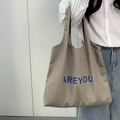 Sac fourre-tout minimaliste en toile marron avec imprimé AREYOU porté par un mannequin - Marron