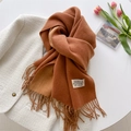 Detail view of brown cashmere-style scarf with fringe on a white tweed jacket - Latte
