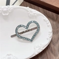 Dettaglio fermaglio a cuore argento con strass blu su un vassoio di ceramica bianca - Cuore-LOVE Verde