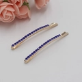 Close-up of two gold-finish hair clips with blue rhinestones on white background - Bobby Pin Blue Rhinestone / Royal Blue