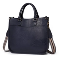 Deep blue leather tote bag with striped fabric strap and elegant stitching on white background - Blue