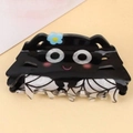 Detailed view of a cute black cat hair claw clip with spider web patterns and blue flower - Spider