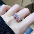 Detailopname van een zilveren vlinderring met vier roze stenen gedragen aan de vinger - Roze Peer Vlinder (JZ3900)