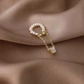Detail of pearl ear cuff with gold tassels and a square zircon on brown silk fabric - Square Zircon Style
