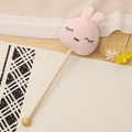 Pink rabbit plush massage hammer with wooden handle on a white patterned mat - 35cm (Massage Stick) / Squinty Eye Rabbit