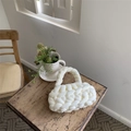 Detailed close-up of a white hand-woven cotton handbag on a rustic wooden table indoors - White