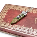 Macro shot of Unakite crystal sword pendant with vintage silver cap on old red book - Unakite