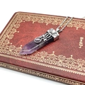 Detail of amethyst hexagonal prism pendant with vintage silver hollow pattern on a notebook - Amethyst