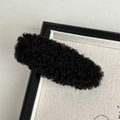 Close-up of a minimalist black plush hair clip with warm autumn winter velvet texture - Black