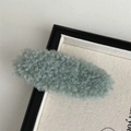 Close-up of a soft plush grey-green oval hair clip with fuzzy texture on a canvas background - Green