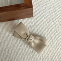 Detailed view of the beige PU leather bow hair clip with textured finish on fabric - Off-white