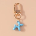 Close-up of blue resin balloon dog keychain with golden U-shaped metal spring clasp - Light Blue