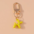 Detail of yellow balloon dog keychain with golden spring buckle on peach background - Yellow