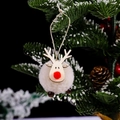 White reindeer Christmas ornament with felt ball body and wooden face on snowy tree branch - White