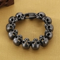Detalle macro de pulsera de calaveras plateadas retro con cierre de cruz gótica punk - Negro Desgastado