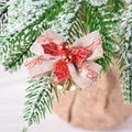 Linen Christmas bow with golden bells and red holly leaves on snow-covered pine branch - Linen Base With Red Leaves Bell Bow