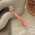 Macro detail of glossy coral pink seamless hair clip on elegant neutral fabric - Glossy Orange Pink