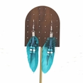 Detail of turquoise feather earrings with bohemian beads on a wooden display stand - Teal