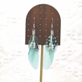 Detail of bohemian long feather earrings with turquoise beads on a wooden stand - Mint Green