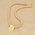 Golden beaded necklace with textured conch shell pendant on beige fabric background - Golden Beaded Conch (E)