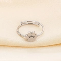 Detailed view of silver cat paw zircon open ring on smooth golden silk fabric - US 6