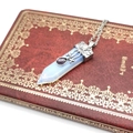 Close-up of hexagonal opal pendant with purple crystal on vintage floral book cover - Opal