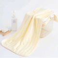 Absorbent light yellow striped coral fleece hand towel draped on a white storage basket - Yellow