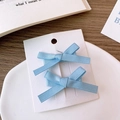 Détail de deux barrettes à nœuds en satin bleu clair sur carte de présentation - Bleu Clair