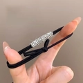 Close-up of sparkling rhinestones on an elastic hair tie held against a neutral background - 1 Piece / Rhinestone Black