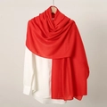 Detail shot of a soft red linen scarf draped on a white shirt showing elegant texture - Red
