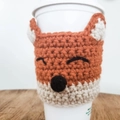 Detail of a handmade crochet fox mug sleeve with 3D ears on a wooden background - Fox Pattern