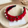 Detail of red knotted headband featuring white, green, and pink pearls on a beige tray - Pearl Red