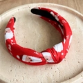 Detail of red Christmas headband featuring Santa Claus prints and knotted fabric design - Santa Claus Print / Red