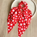 Detail of red hair scrunchie with white stars and bow ribbon on a stone tray - Star Red Ribbon