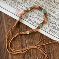 Detail of bohemian woven belt with turquoise beads and flower accents on vintage paper - Brown Cord Blue Flower Bead Style