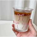 Nahaufnahme einer Glastasse mit rosa Schleifenmuster und Schichtkaffee mit Milch - 330ML / Kurze Tasse mit Rosa Schleife und Ausgestelltem Rand