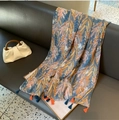 Écharpe en coton et lin bleu avec imprimé floral et glands drapée sur un canapé gris - Floral Bleu Orange