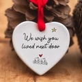 Heart-shaped ceramic ornament with red ribbon and Christmas message on rustic background - We Wish You Lived Next Door