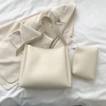 Détail d'un grand sac cabas beige minimaliste avec sa pochette assortie sur fond neutre - Blanc