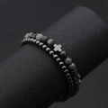 Dettaglio di due braccialetti di perline con ciondolo a croce su espositore nero - 4mm Ematite + 6mm Pietra Flash Nera