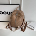 Detailed view of khaki pebbled leather backpack with multiple zippers and woven strap - Khaki