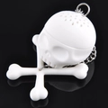 White skull and crossbones silicone tea infuser with metal chain on black background - Skull