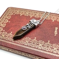 Detailed view of Tiger Eye sword pendant necklace on a vintage red book with golden ornaments - Tiger's Eye