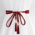 Cintura a corda intrecciata rosso scuro con chiusura dorata e nappe su abito bianco - Rosso