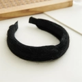 Close-up of black textured wool fabric headband with plush yarn material on a desk - Twisted Black