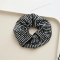 Detailed view of a black scrunchie with sparkling silver sequins in a grid pattern - Sequin
