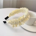 Detail of elegant beige pleated satin headband with wavy texture on a minimalist table - Off White