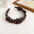 Detail shot of a dark brown pleated fabric headband on a minimalist white table setup - Brown
