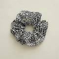 Nahaufnahme eines schwarz-weißen Scrunchie mit Leopardenmuster und weicher Stofftextur - Weißer Leopardenmuster